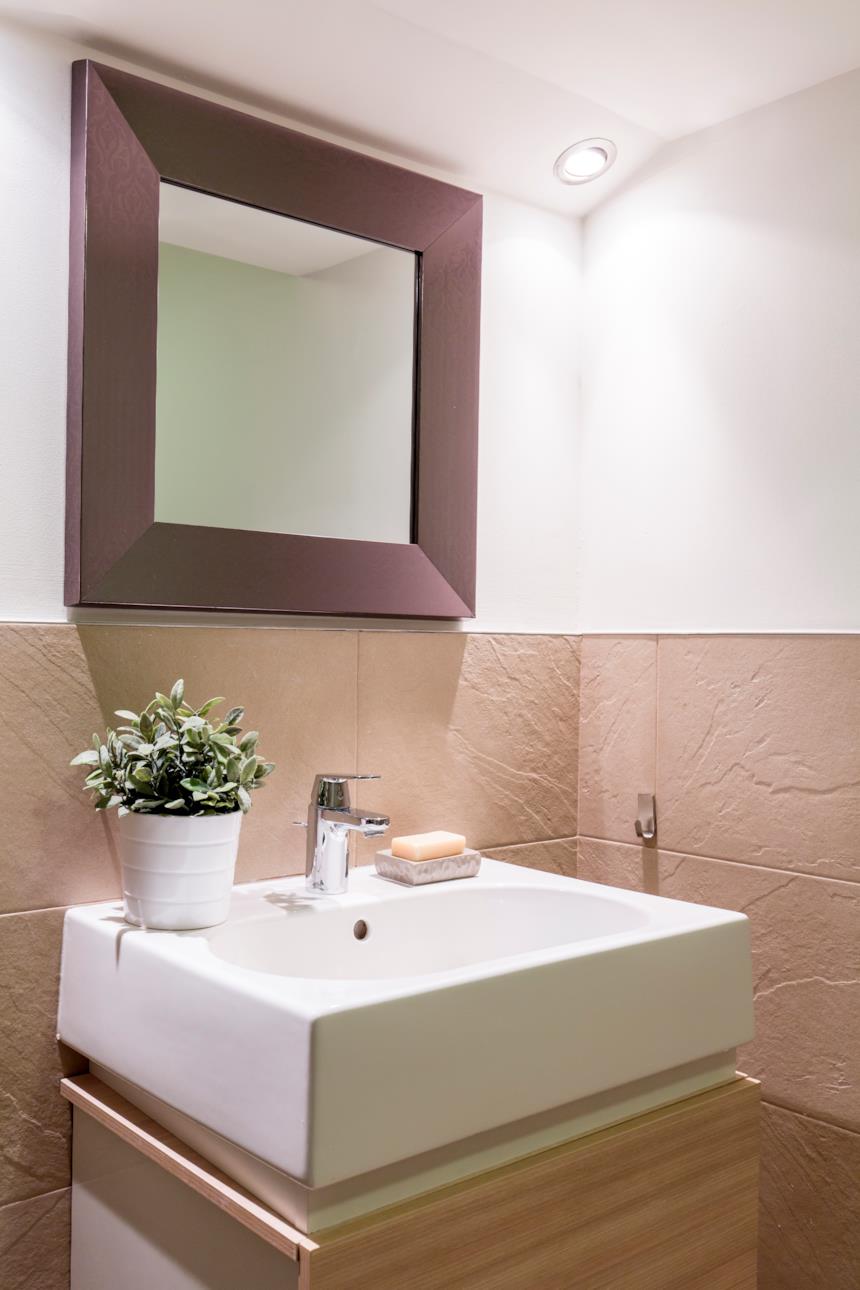 Bagno con piastrelle beige e specchio marrone