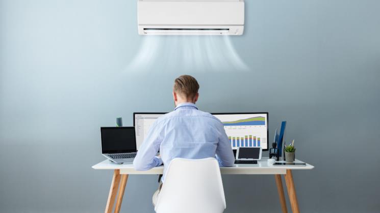 Ragazzo alla scrivania sotto il climatizzatore acceso 