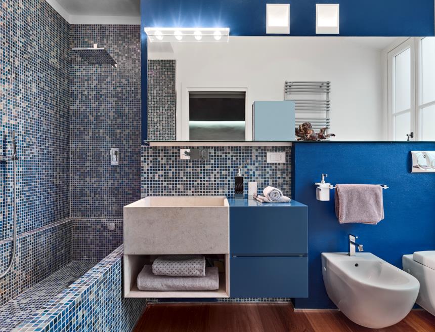 Bagno con parete a mosaico blu e mobile blu 