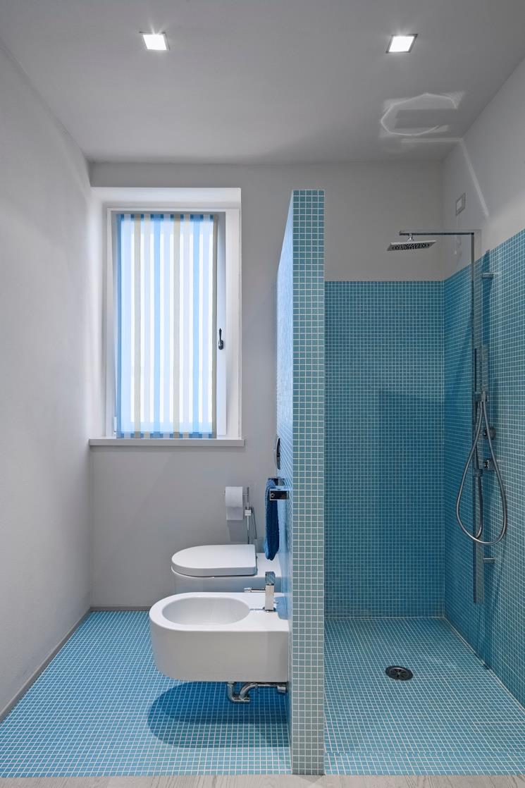 Bagno a mosaico blu con coppia di sanitari bianchi