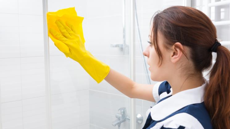 Donna pulisce il box doccia