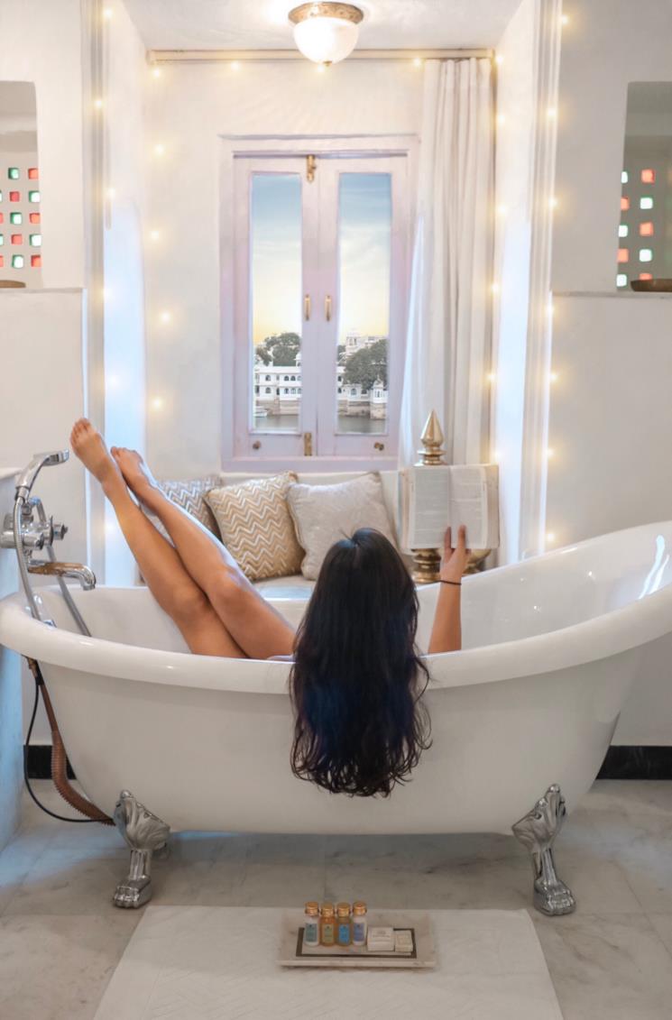 Donna legge un libro rilassandosi in una vasca da bagno freestanding 