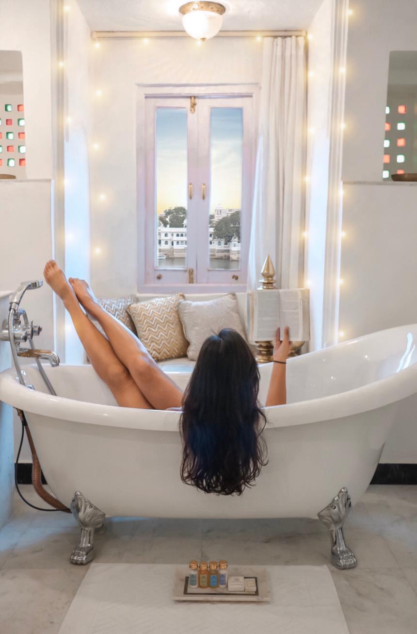 Donna legge un libro rilassandosi in una vasca da bagno freestanding 