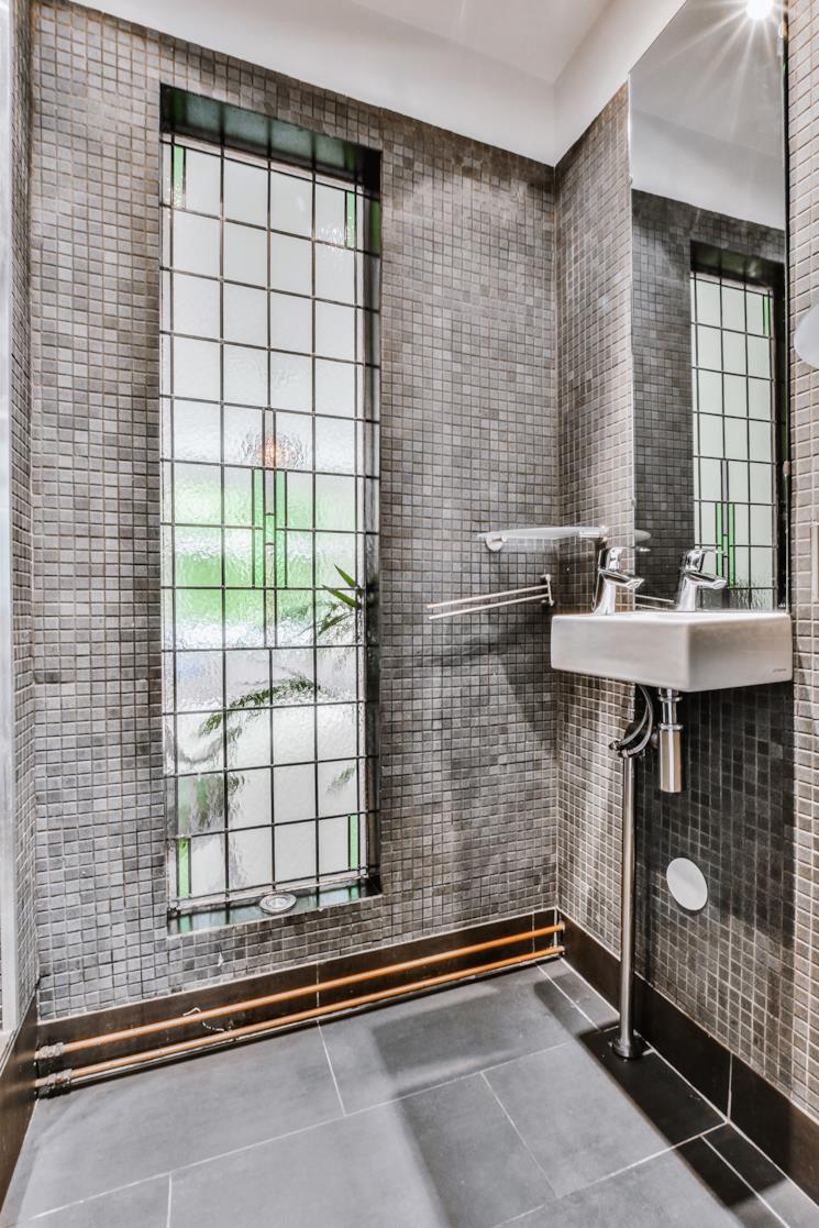 Bagno con parete a mosaico grigia