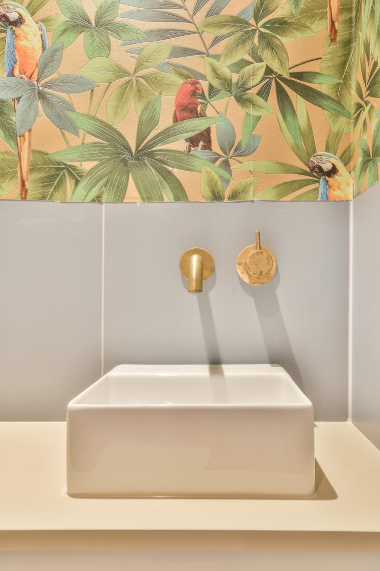 Lavandino da appoggio sormontato da carta da parati decorata con foglie e pappagalli
