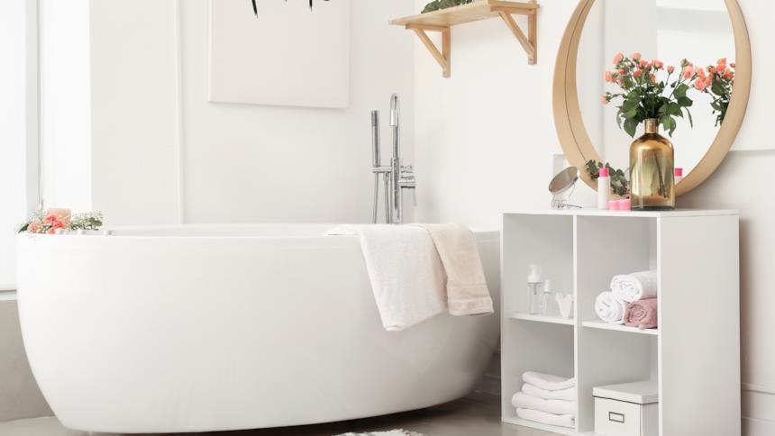 Vasca freestanding con accanto un mobile portaoggetti 