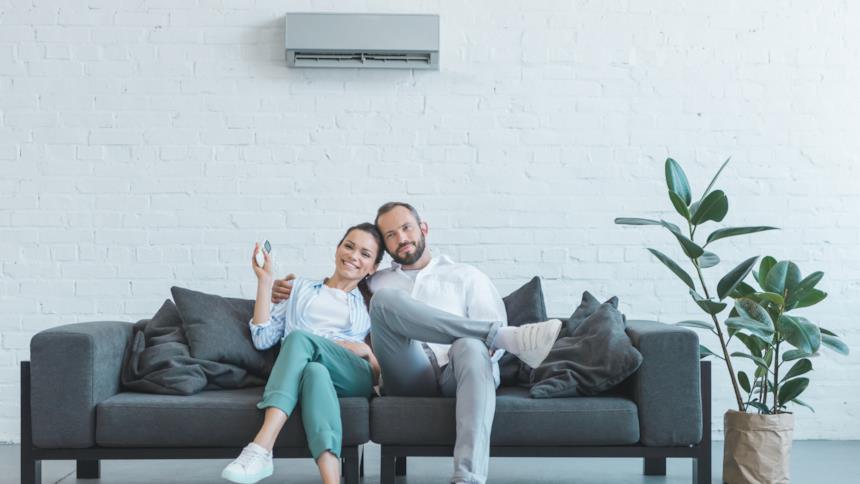 Coppia seduta sul divano sotto un climatizzatore 