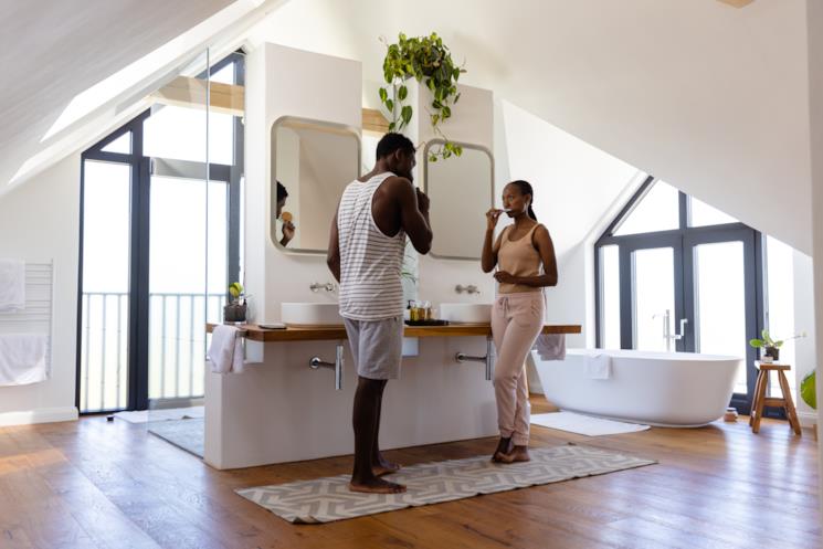 Coppia si lava i denti in un grande bagno con doppio lavabo e doppio specchio