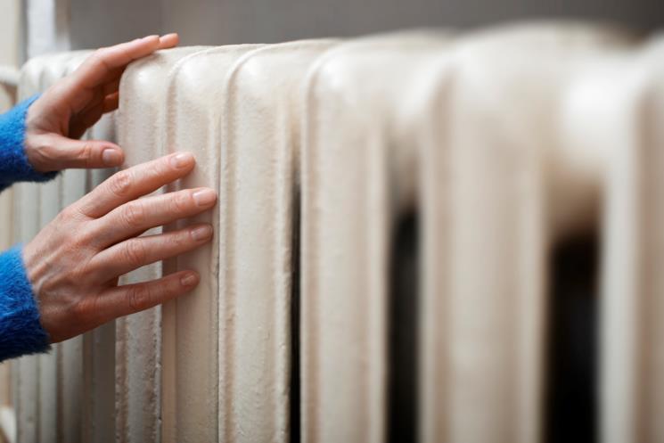 Donna sente se il termosifone è caldo poggiandovi le mani