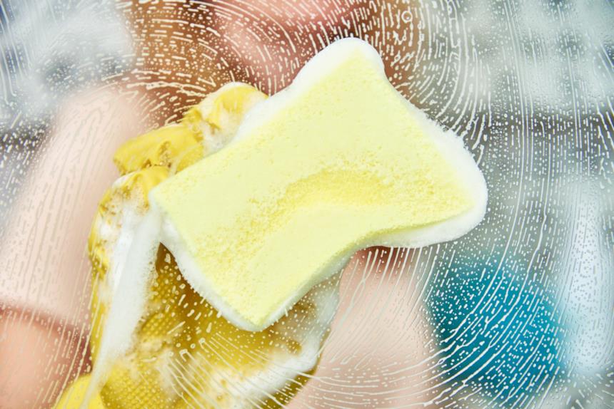 Spugnetta insaponata passata sul vetro della doccia 