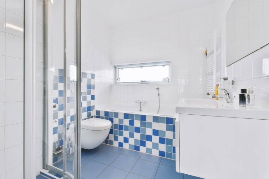 Bagno con pavimento blu e parete a piastrelle bianche e blu 
