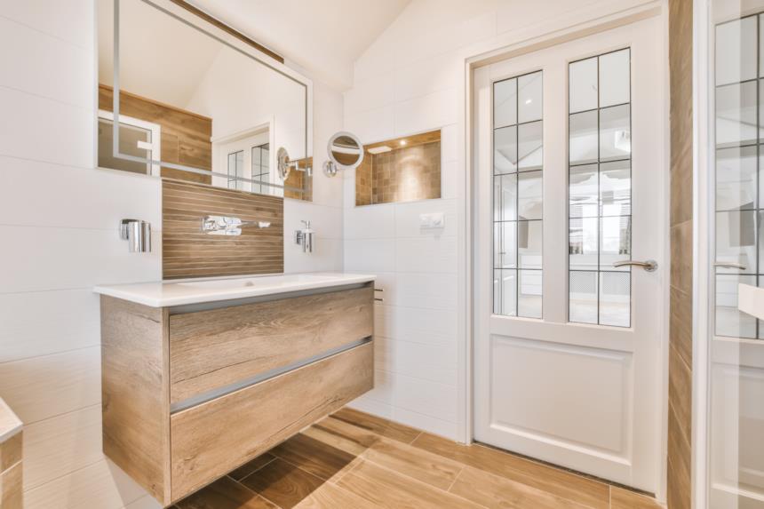 Bagno bianco con mobili e pavimento in legno 