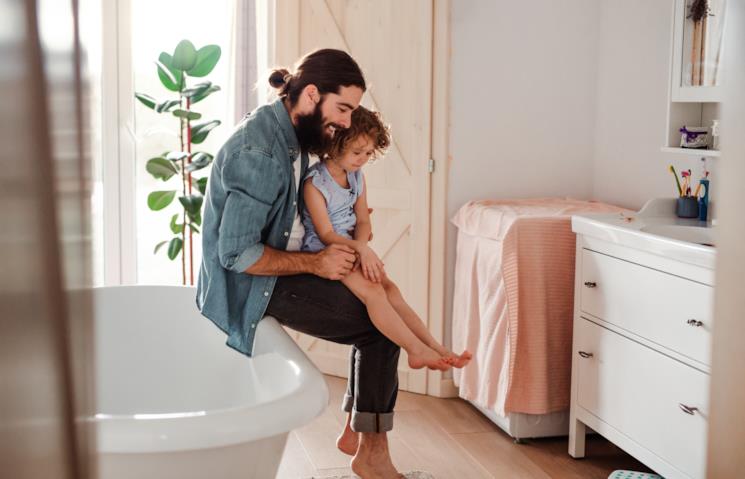 Padre tiene in braccio a bordo vasca la figlia