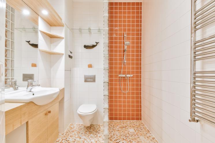 Bagno con mattonelle della doccia arancioni e pavimento a mosaico della medesima tonalità 