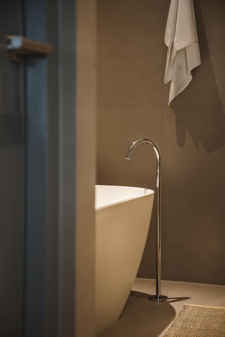 Miscelatore a pavimento senza doccetta vicino a una vasca freestanding