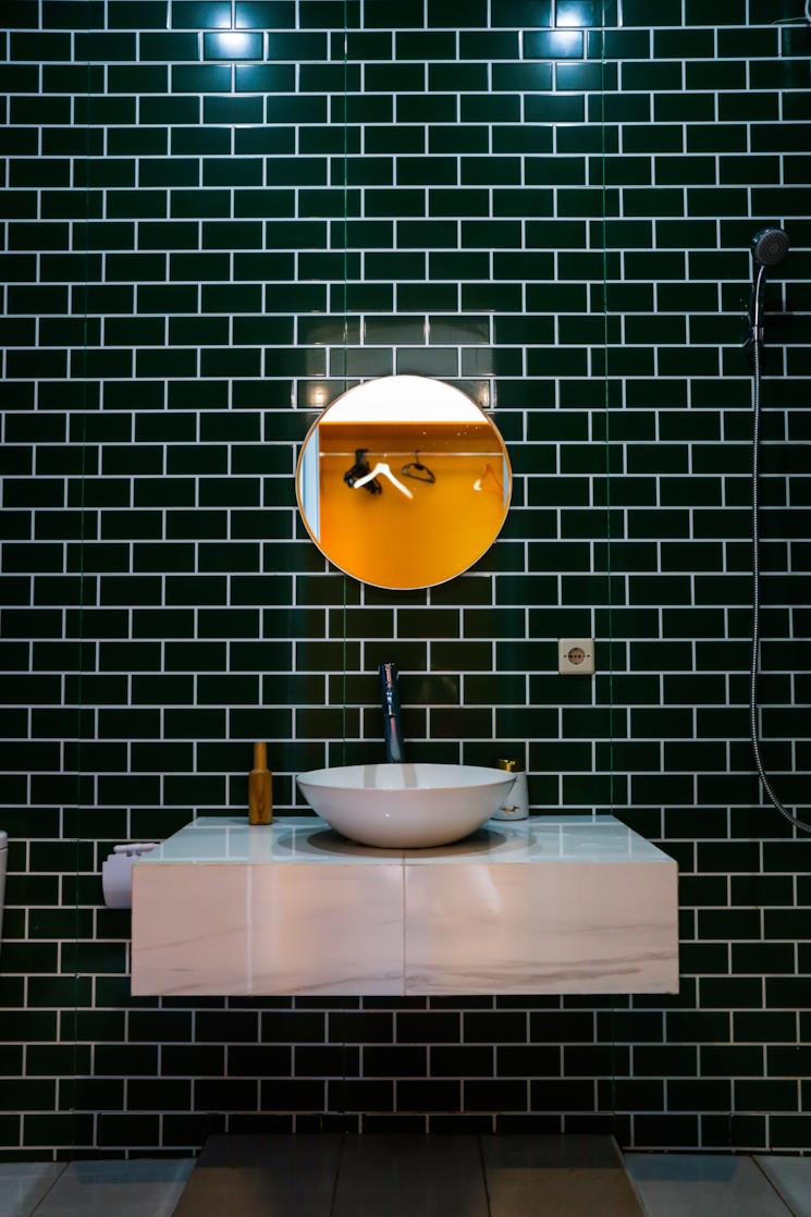 Bagno con piastrelle nere e console in marmo 