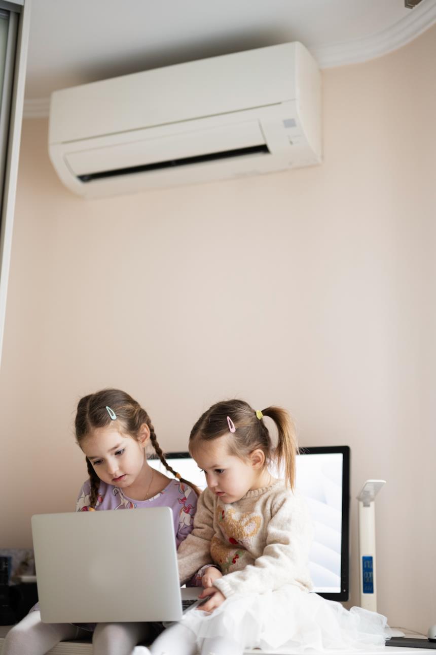 Bambine al computer in una stanza con climatizzatore