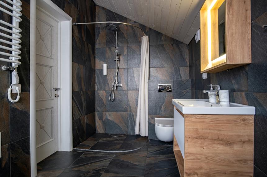 Bagno con rivestimenti scuri e mobili in legno 