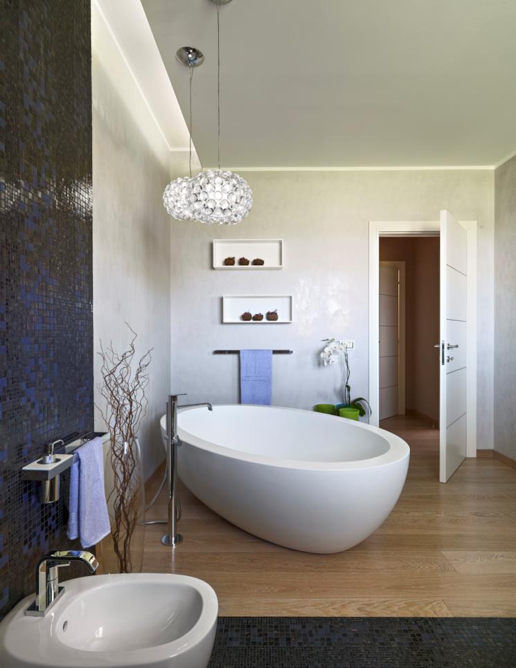 Bagno con vasca freestanding sovrastata da lampadari 