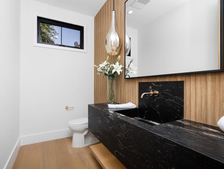 bagno con parete e pavimento in legno e lavabo in marmo nero elegante