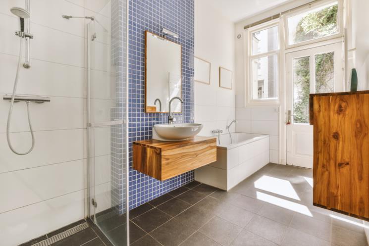 Bagno con parete a mosairco blu e mobile portalavabo in legno 