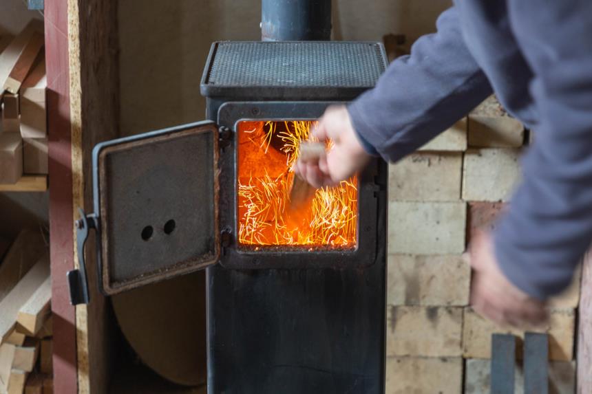 Uomo aggiunge legna alla caldaia a legna