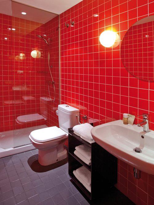 Bagno con il box doccia fatto di piastrelle rosse che proseguono poi sul muro