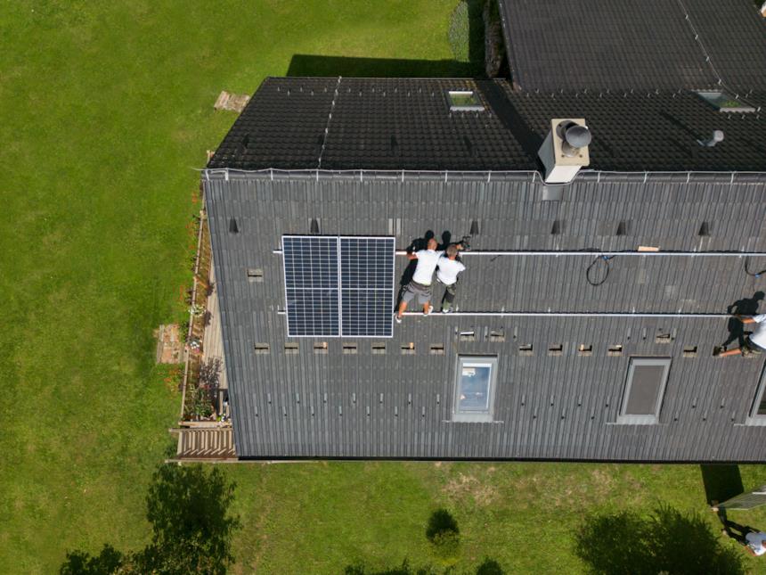 Tecnici installano pannelli fotovoltaici sul tetto di una casa 
