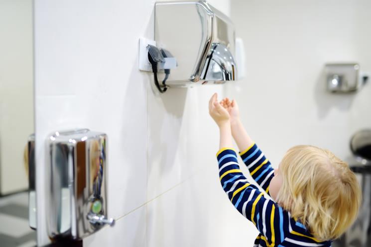 Bambino usa l'asciugamani elettrico 