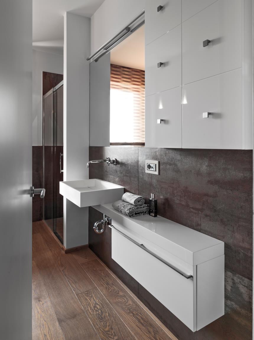 Bagno con mobili bianchi e rivestimenti scuri 