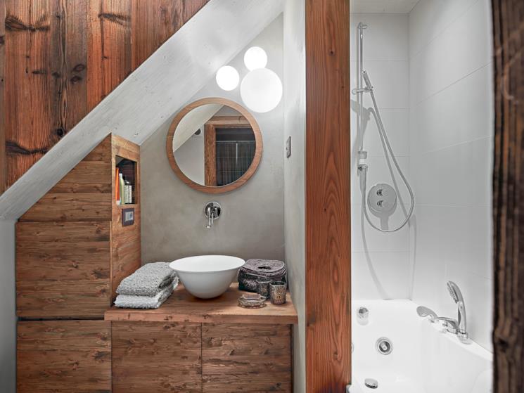 Bagno con mobili in legno, lavandino da appoggio e specchio tondo