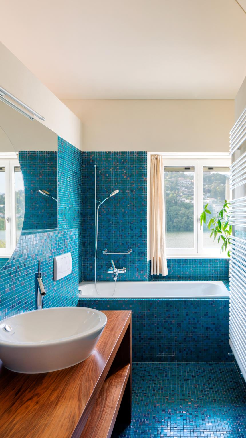 Bagno con piastrelle piccole blu e mobili in legno