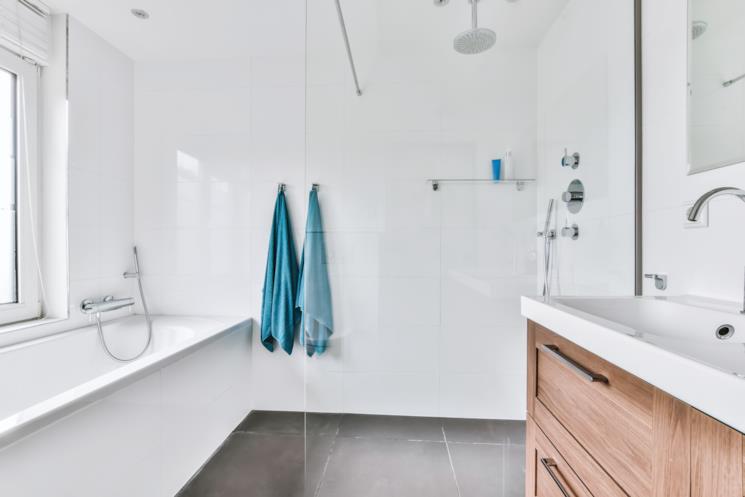 Bagno bianco con teli doccia blu e mobile portalavabo in legno 