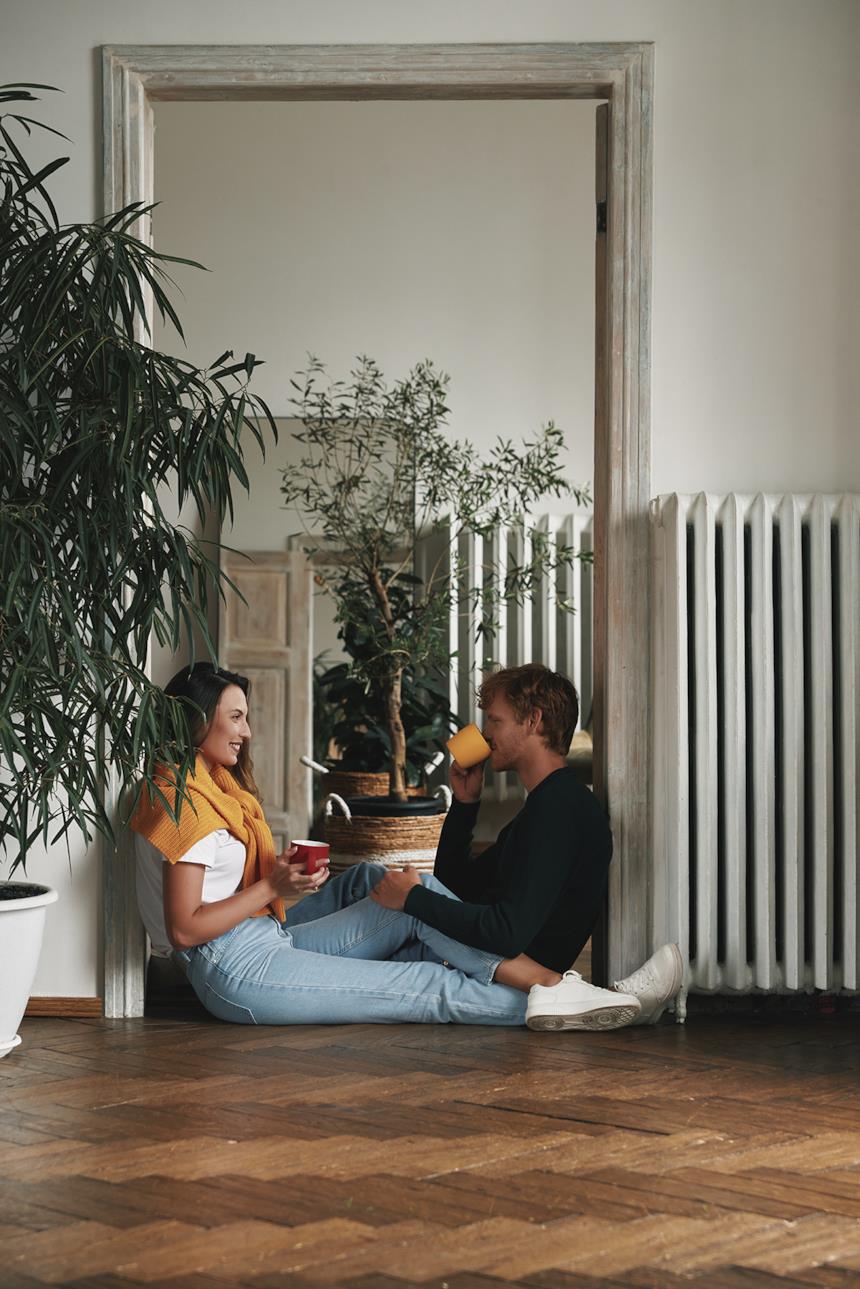 Coppia sorseggia una bevanda vicino al termosifone 