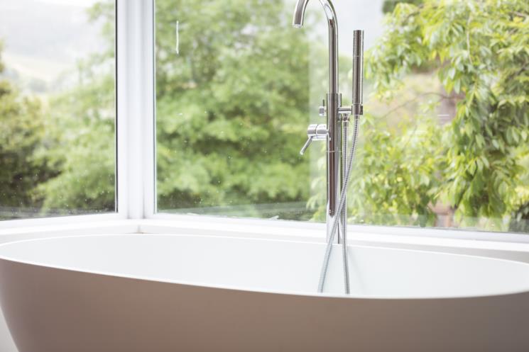 Miscelatore a pavimento con doccetta vicino una vasca freestanding