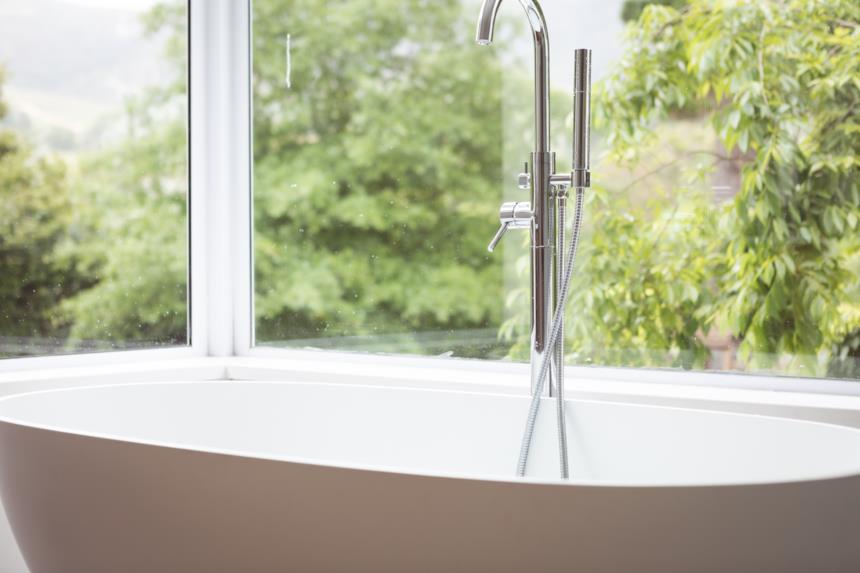 Miscelatore a pavimento con doccetta vicino una vasca freestanding 