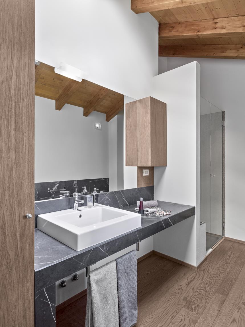 Bagno con console in marmo e pavimento in parquet 