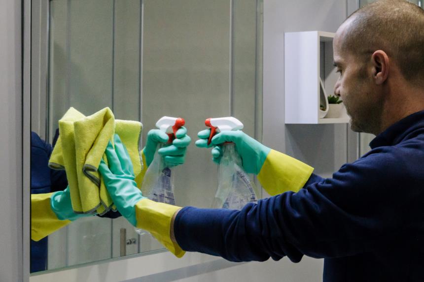 Uomo pulisce lo specchio del bagno 