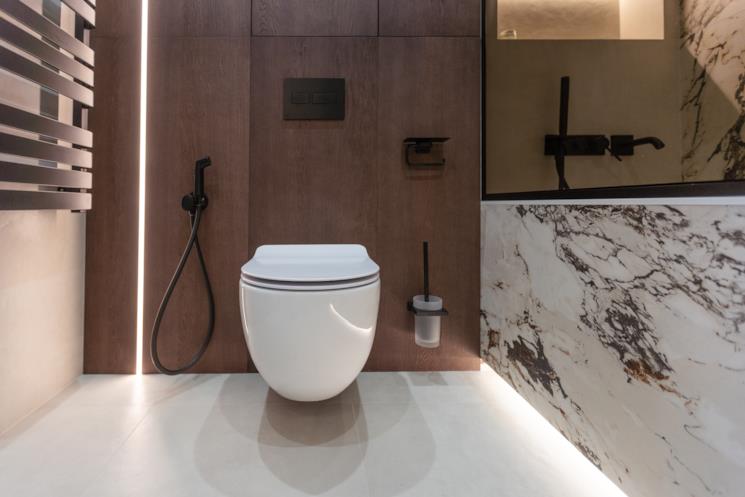 WC a filo muro accanto a una vasca in marmo 