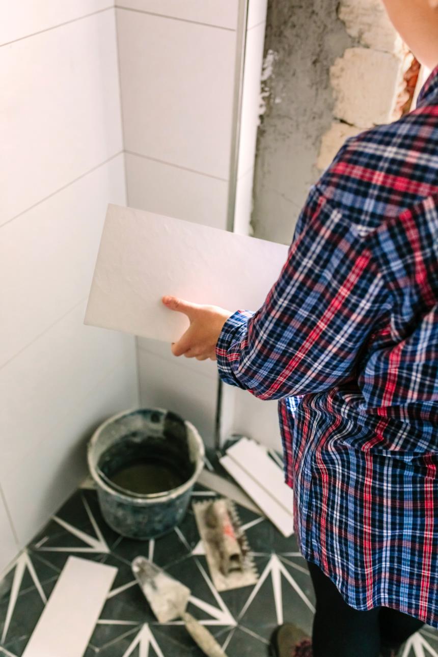 Operaio mette in posa le piastrelle nel bagno 