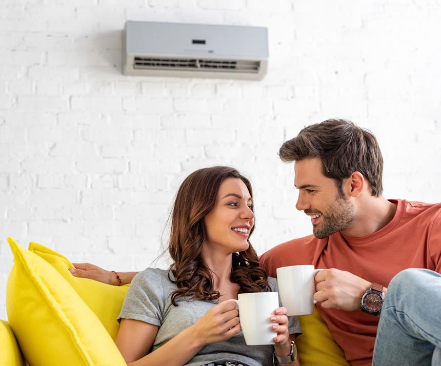 Climatizzatore appeso alla parete con sul divano una coppia