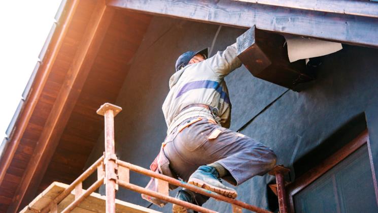 Operaio monta i pannelli isolanti su una casa