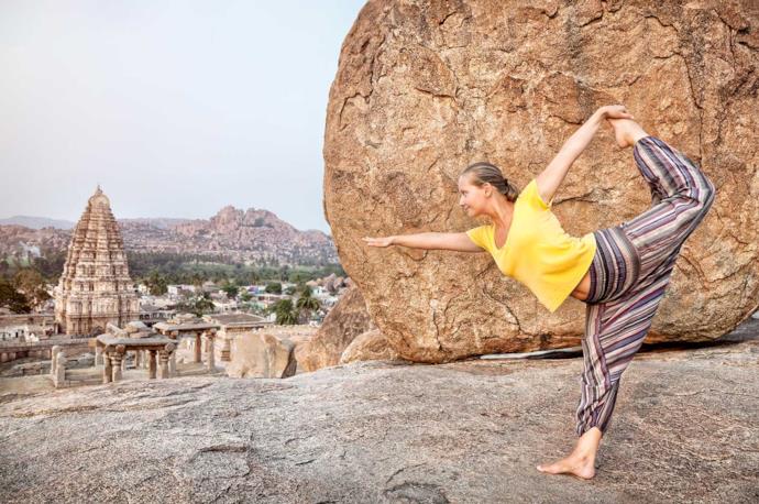 Giovane donna in posizione Yoga presso un tempio indiano