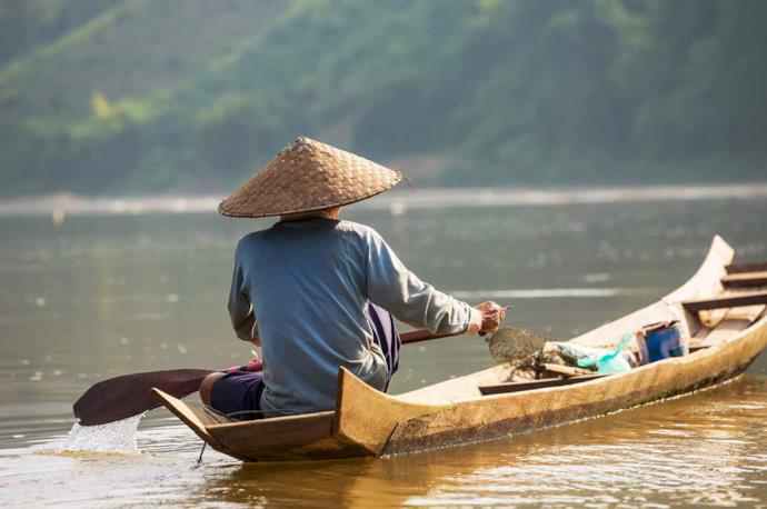 Uomo in Laos su barca tradizionale