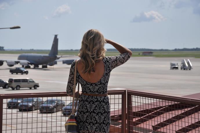 Una donna di spalle che guarda gli aerei partire.
